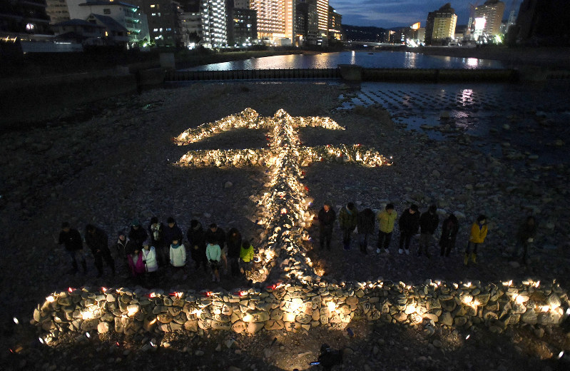 「生」の文字をかたどった石積みの前で黙とうする人たち=兵庫県宝塚市で2019年1月16日午後5時46分、久保玲撮影