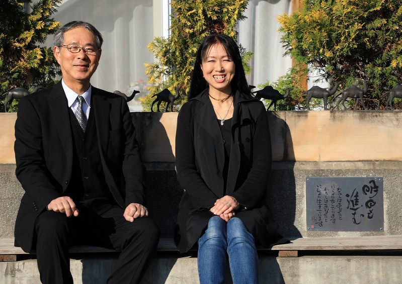 明日香さんを偲ぶモニュメントに座る母の桐田寿子さん(右)と桐淵博さん=さいたま市北区で2018年12月、梅村直承撮影