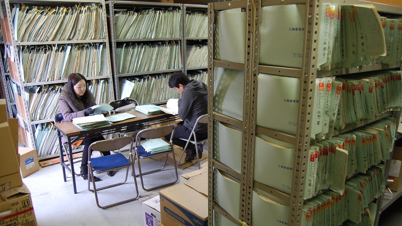 古い診療記録を調べる人たち。MID-NETはこうした情報を、製薬会社を通さずに収集する