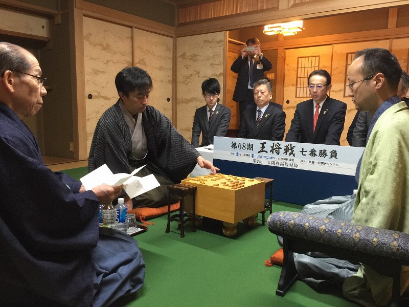 王将戦七番勝負第2局で、封じ手の7八銀を指す久保利明王将(左から2番目)。右端は渡辺明棋王=大阪府高槻市の山水館で2019年1月27日午前8時59分、丸山進撮影