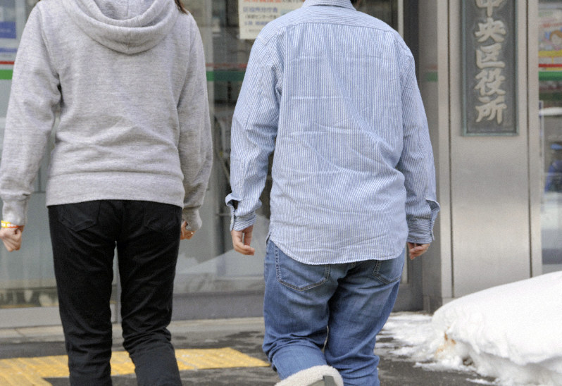 婚姻届を提出するため札幌市中央区役所に入る女性カップル=同市中央区で