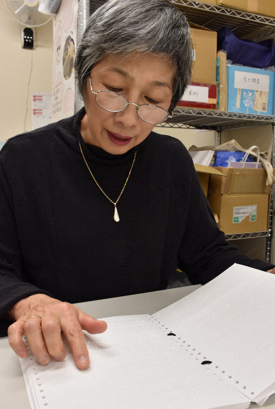 点訳した文書を指で触れて確認するボランティアの鈴木静代さん=東京都文京区で2018年12月7日、柳楽未来撮影