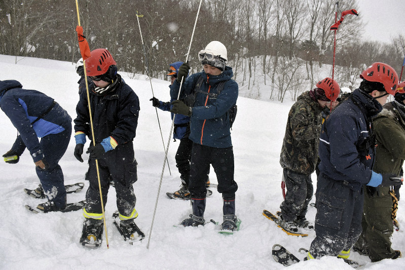 ゾンデ棒を使って雪中のリュックサックを探す中村聡也記者(中央)=秋田仙北市の秋田駒ケ岳で2019年2月1日、田口俊彦撮影