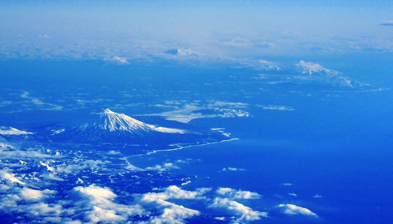 北海道標津町の上空から望む国後島の爺爺岳(左)。右奥は択捉島=2019年1月30日午前8時17分、本社機「希望」から