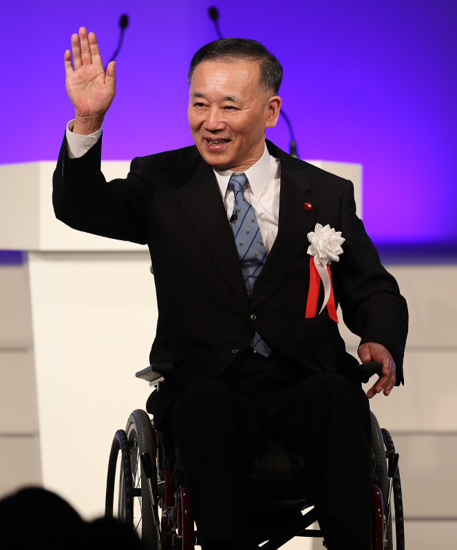 車椅子で登壇し、手を上げる谷垣禎一前総裁=東京都港区で2019年2月10日、玉城達郎撮影