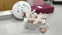 白と薄紅の半球を合わせた小さな玉を一つずつ和紙でくるんだ干菓子「二人静（ににんしずか）」＝2019年2月19日、田中学撮影