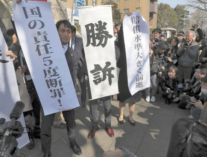 判決後に「勝訴」などと書かれた幕を掲げる弁護士ら=横浜市中区で2019年2月20日午前10時半、和田大典撮影