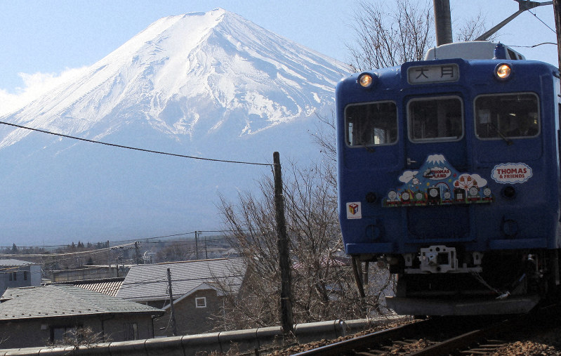 富士山を背にした「トーマスランド号」のラストラン=山梨県富士吉田市の富士急行線・富士山駅ー月江寺駅間で2019年2月23日午前11時32分、小田切敏雄撮影
