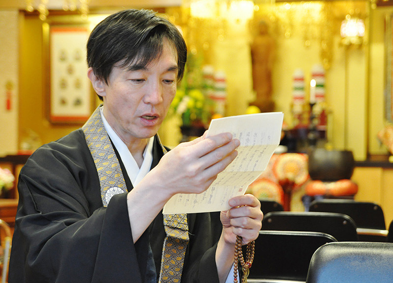 東日本大震災で被災した女性からの手紙を読む鍋島直樹さん。「宗教者に役割があることを教えてもらった」と語る=神戸市中区で、花澤茂人撮影