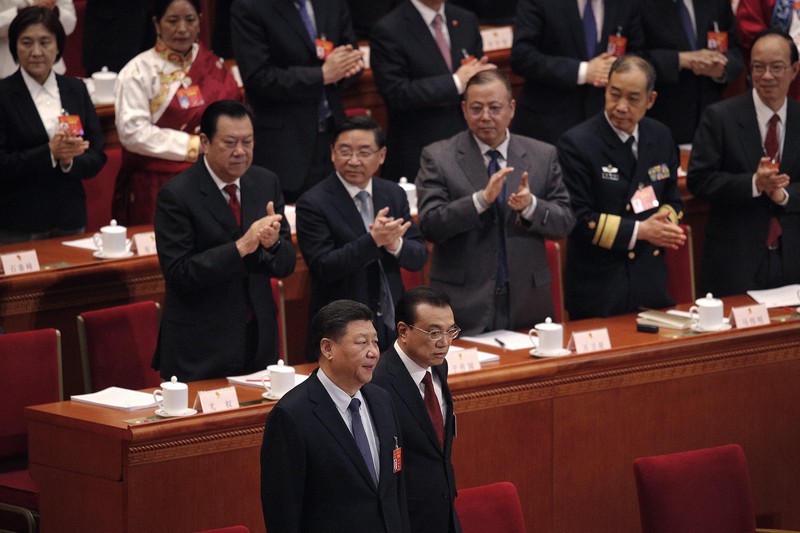 全国人民代表大会の会場に入り、拍手で迎えられる習近平国家主席(前列左)と李克強首相(同右)=北京の人民大会堂で2019年3月5日、AP