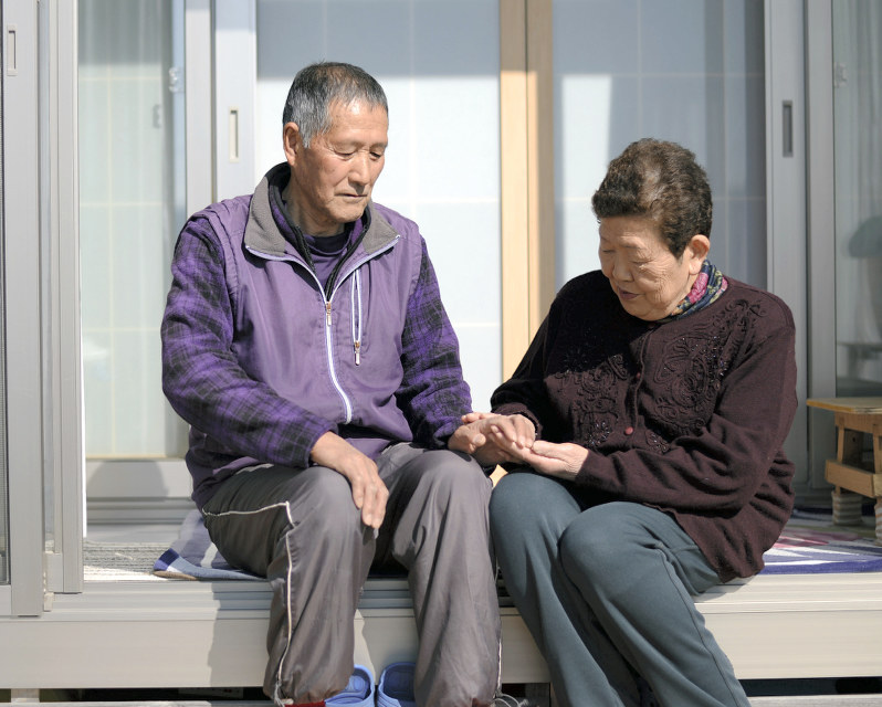 自宅の縁側で語らう大川貞男さん(左)と妻ヒメ子さん。貞男さんは津波で左腕に後遺症が残り、漁師への復帰は断念せざるを得なかった=岩手県山田町で2019年2月23日、喜屋武真之介撮影