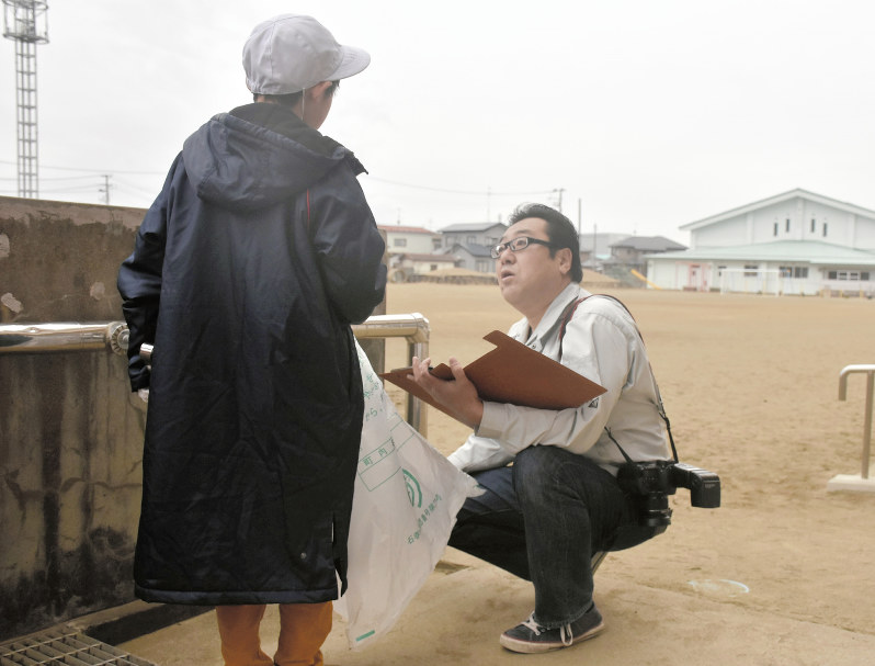 清掃活動の取材で男児に話を聞く平塚宏行さん(右)=宮城県石巻市で2019年2月6日
