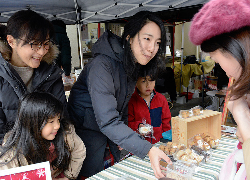 食品関係のイベントで米粉のスコーンなどを販売する冨井聖子さん(中央)。左隣が長女智爽さん、右隣は長男遥人(はると)さん=大阪市中央区で、金志尚撮影