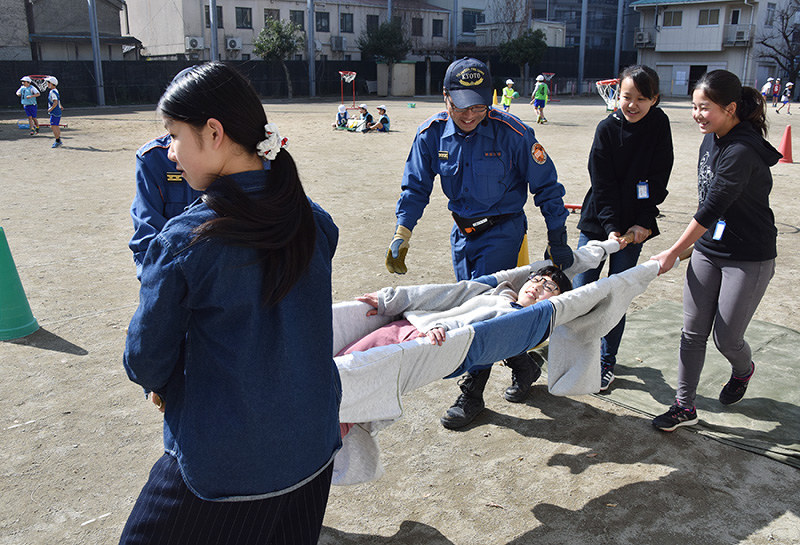 トレーナー3枚をつなげた簡易式担架で同級生の搬送訓練を行う児童たち=京都市上京区で、篠田直哉撮影