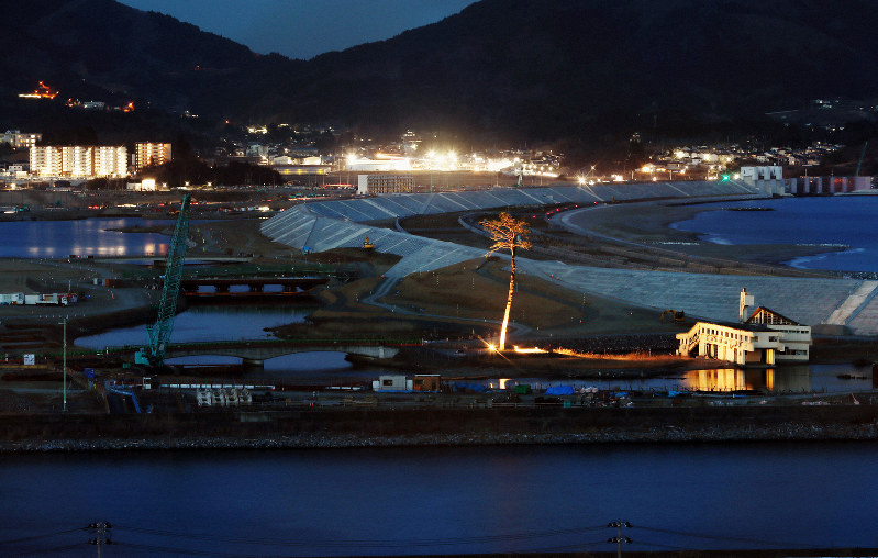 防潮堤の工事が続く陸前高田市。日が暮れると、薄暗い海沿いにライトアップされた「奇跡の一本松」が浮かんだ=岩手県陸前高田市で2019年3月9日、小川昌宏撮影