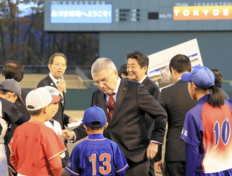 東京五輪で野球・ソフトボール会場となる福島県営あづま球場の視察に訪れ、球児らと交流する国際オリンピック委員会のトーマス・バッハ会長(中央)と安倍晋三首相(後方中央)=福島市で2018年11月24日、代表撮影