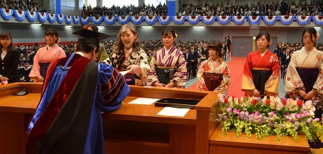 学位記を受け取るため壇上に並ぶ各学部代表の女子学生たち