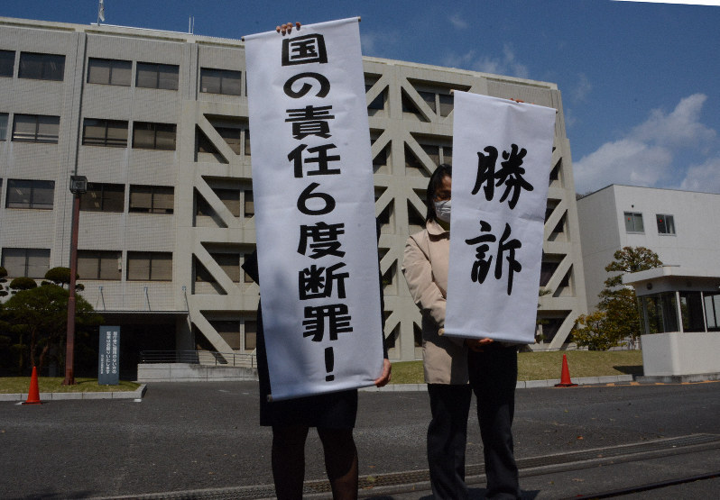 松山地裁の判決を受け、「勝訴」などと書かれた旗を掲げる支援者ら=松山市で2019年3月26日午後1時13分、花澤葵撮影