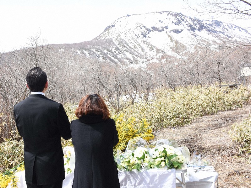 追悼式に出席し、現場の茶臼岳を見上げながら手を合わせる鏑木悠輔さんの父浩之さんと母恵理さん=栃木県那須町湯本で2019年3月26日午前11時37分、萩原桂菜撮影