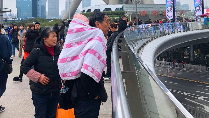 街中で孫をおんぶするおじいちゃん=中国・上海市内で2019年3月10日、筆者撮影