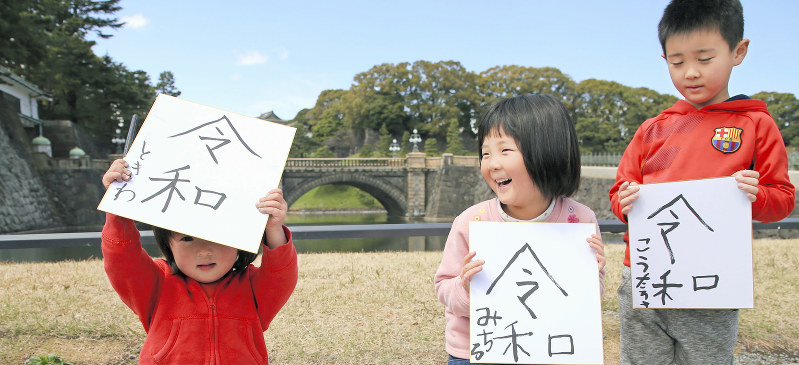 皇居前広場で色紙に「令和」の文字を書いて、掲げる子どもたち=東京都千代田区で2019年4月1日午前11時49分、小川昌宏撮影