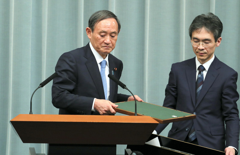 額縁を下向きで受け取って新元号の発表記者会見に臨む菅義偉官房長官(左)=首相官邸で2019年4月1日午前11時41分、長谷川直亮撮影