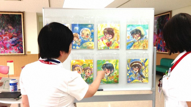 村岡さんの描いた似顔絵を見る看護師たち=村岡ケンイチさん提供