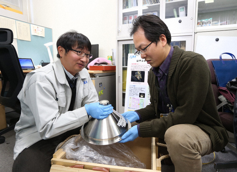 探査機はやぶさ2の打ち上げ前、小惑星にクレーターを作る実験に使う衝突装置の模型を確認する佐伯孝尚さん(左)と津田雄一さん=相模原市のJAXA相模原キャンパスで2013年、武市公孝撮影