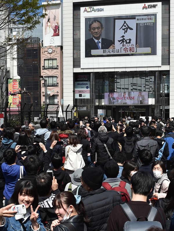 人々が見守る中、菅義偉官房長官が新元号「令和」を発表する様子が街頭の大型ビジョンに映し出された=東京都新宿区で4月1日、竹内紀臣撮影