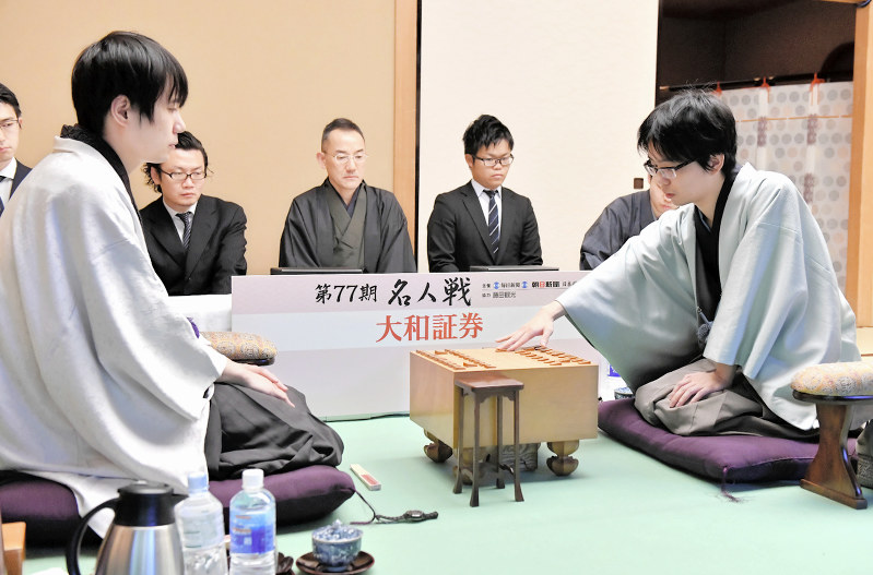 指し直し局で初手を指す挑戦者の豊島将之王位(手前右)。手前左は佐藤天彦名人=東京都文京区のホテル椿山荘東京で2019年4月11日午前9時、宮間俊樹撮影