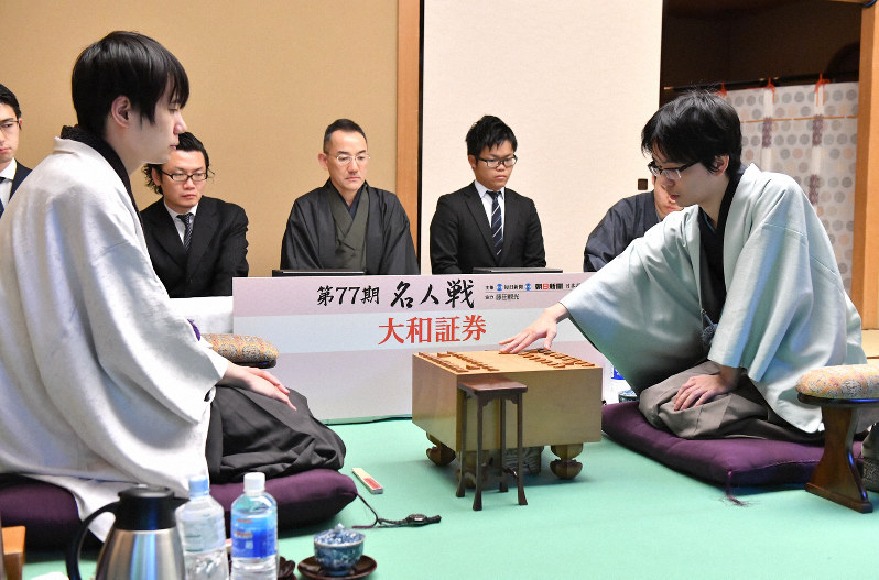 千日手から一夜明け、指し直し局で初手を指す挑戦者の豊島将之王位(手前右)。手前左は佐藤天彦名人=東京都文京区のホテル椿山荘東京で2019年4月11日午前9時、宮間俊樹撮影