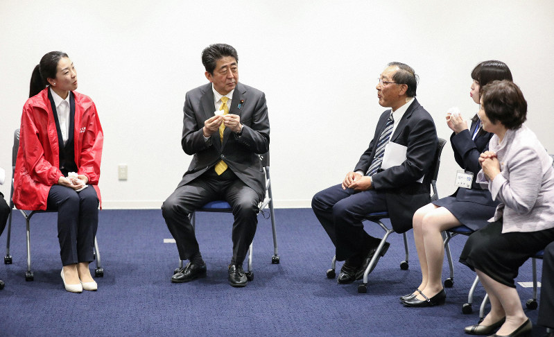 福島県大熊町役場の新庁舎内で、地元産のお米で作ったおにぎりを食べる安倍晋三首相(左から2人目)=2019年4月14日午後0時39分(代表撮影)