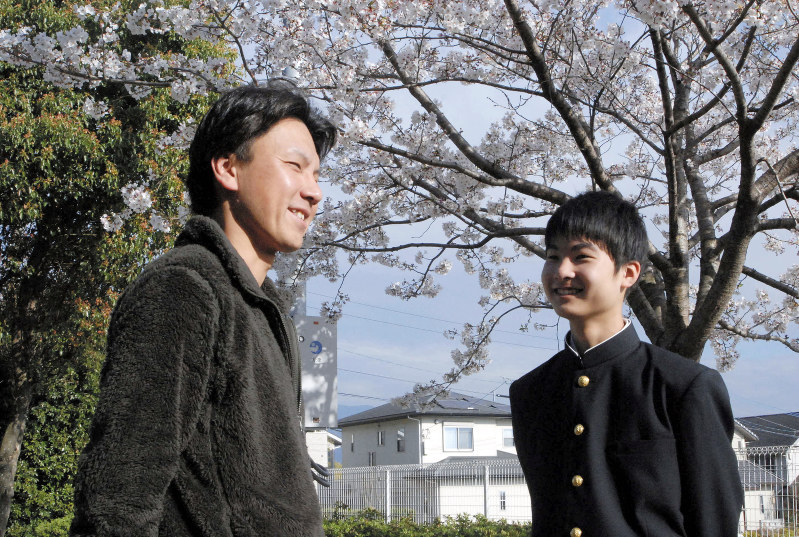 桜の下で制服姿の郁斗さん(右)と語らう嶋崎さん=熊本県大津町で2019年4月5日、中里顕撮影