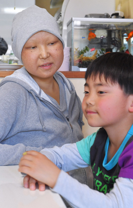 自宅で療養する梶原瑠美子さん。リビングで小学校から帰ってきた長男蒼佑さん(手前)と過ごす=熊本県南阿蘇村で2019年4月15日、森園道子撮影