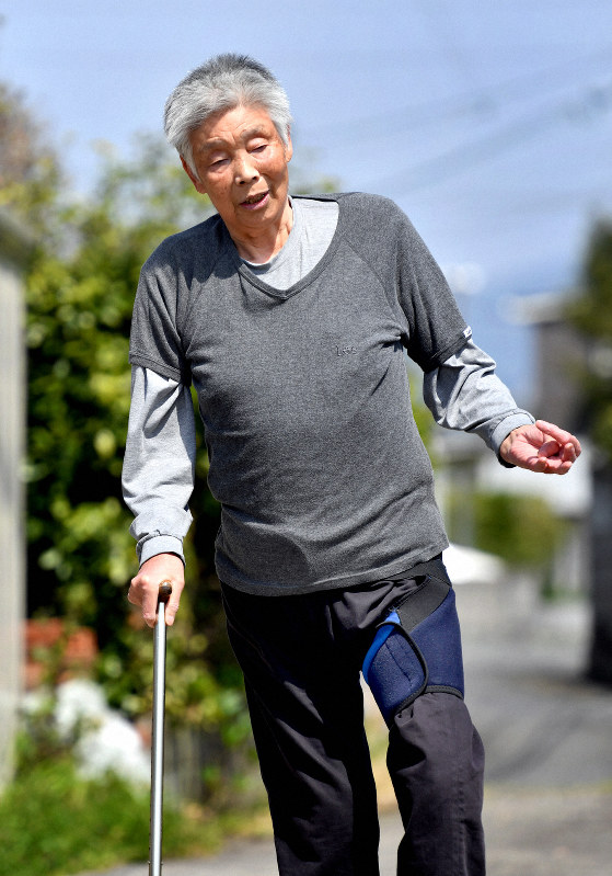自宅近くの路地を歩く渡辺数美さん。短い距離でもつえは手放せない=熊本県内で2019年4月9日、野田武撮影