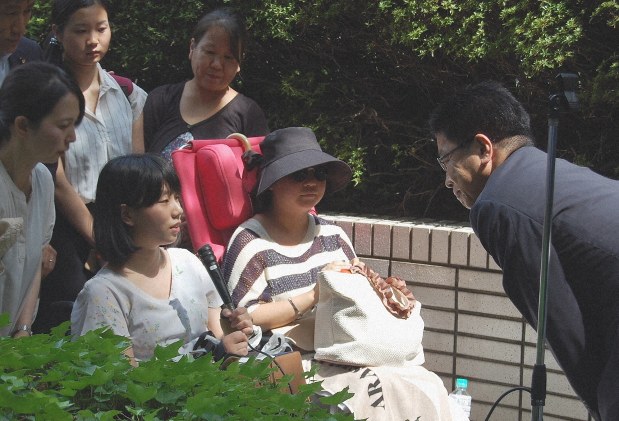 HPVワクチンの副作用被害を受けたとして訴訟を起こしている原告の女性らと、加藤勝信厚生労働相(当時)=厚労省前で2017年8月