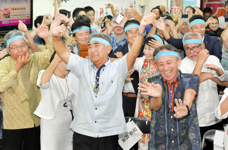 衆院沖縄3区補選で当選確実となり、玉城デニー・沖縄県知事(右)らとカチャーシーを踊って喜び合う屋良朝博氏(中央)=沖縄市で2019年4月21日午後8時13分、森園道子撮影