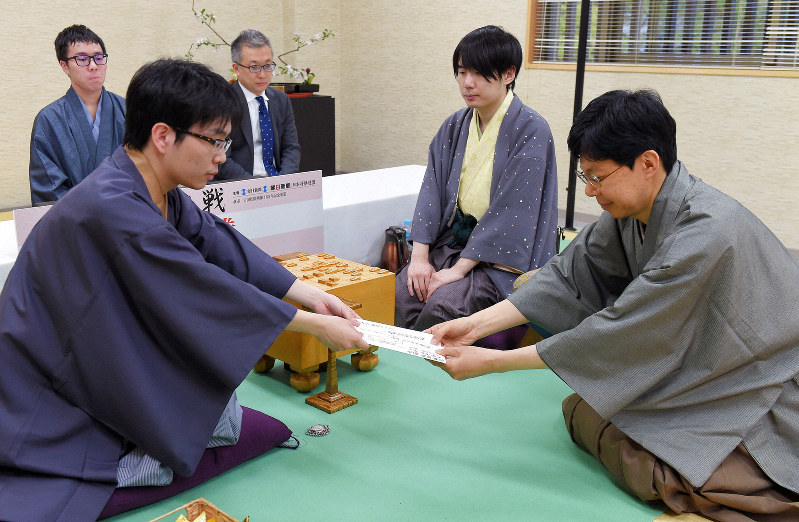 封じ手を立会の谷川浩司九段(右)に手渡す挑戦者の豊島将之王位(左)。中央は佐藤天彦名人=山口県萩市の松陰神社立志殿で2019年4月22日午後6時38分、上入来尚撮影