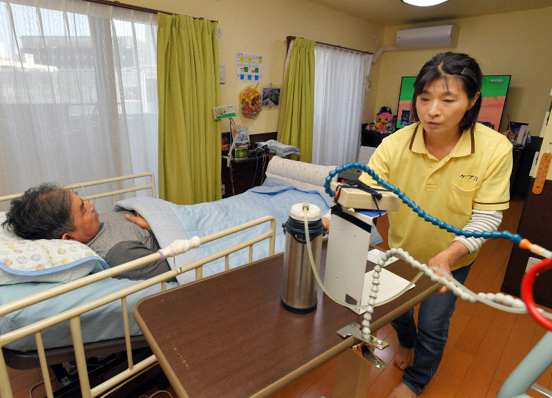 利用者の中村豊さんの介護をするヘルパーの荒木美奈子さん(右)=福岡市博多区で2019年4月27日、森園道子撮影