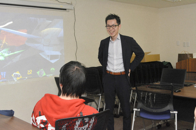 「トコステーション」でゲームを楽しむ利用者を見守る宮武将大さん=高松市瓦町1で2019年4月23日午後4時半、金志尚