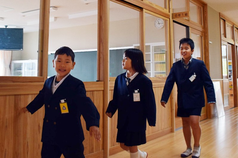 避難所で一緒に過ごした満生さん(右端)の案内で校舎を見学する熊谷さん(左端)=福岡県朝倉市で