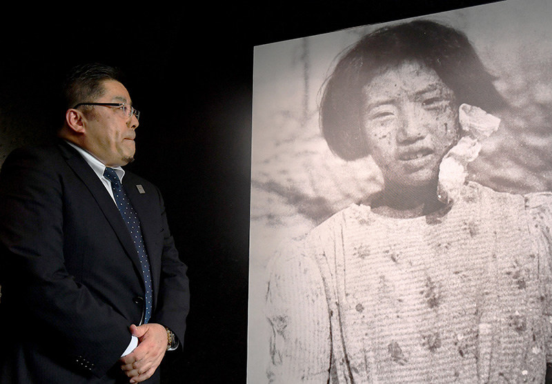 リニューアルオープンした原爆資料館本館で、被爆3日後の母幸子さんを捉えた写真を見つめる藤井哲伸さん=広島市中区で、山田尚弘撮影