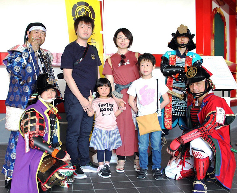観光客と記念撮影する「信長隊安土衆」の“明智光秀”(後列右端)ら=滋賀県近江八幡市安土町桑実寺の「安土城天主 信長の館」で、同市提供