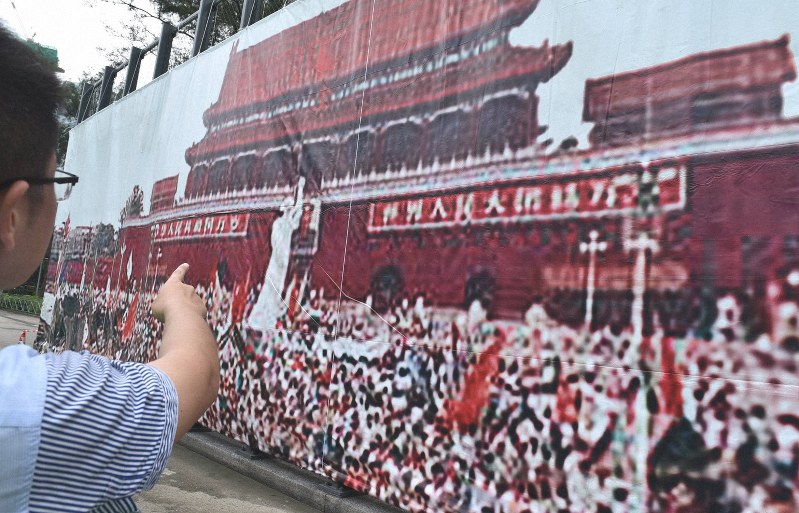 天安門広場に集まる学生らを写した1989年当時の写真に見入る男性。「中国の民主化を促す力になりたい」とデモに参加する決意を語った=香港中心部のビクトリア公園で2019年6月3日15時10分、福岡静哉撮影