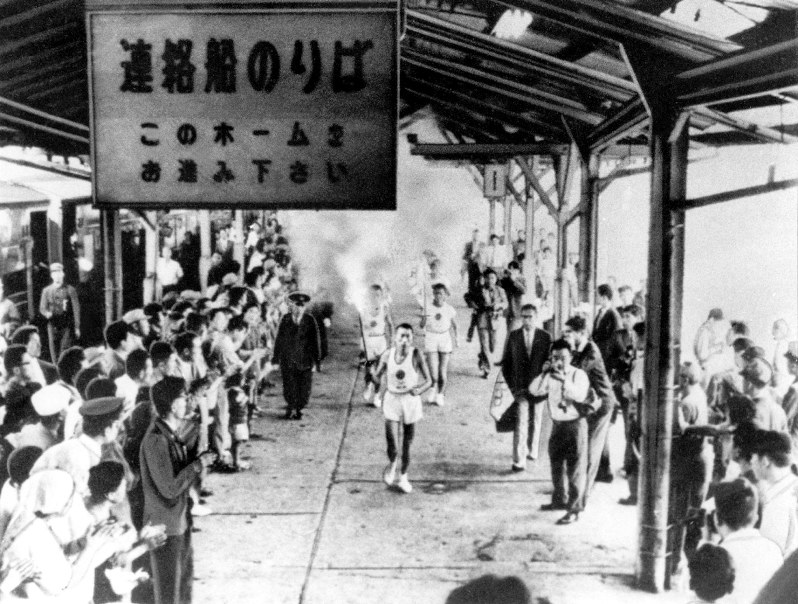 青森駅のホームで大勢の人たちの声援を受けながら走る聖火ランナー=1964年9月17日