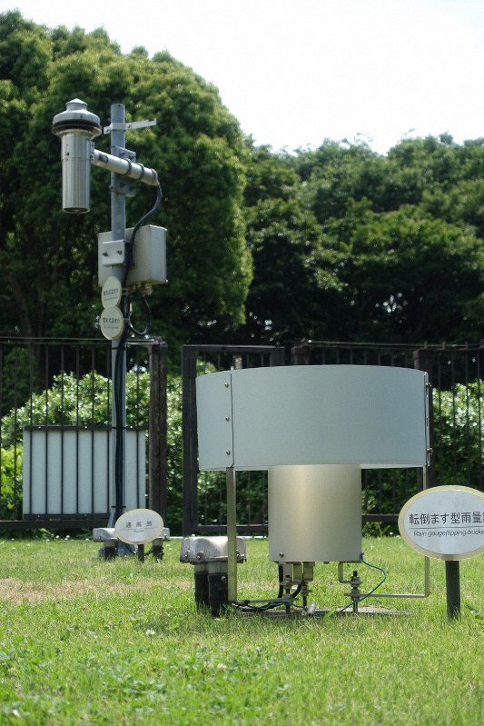 気象庁の温度・湿度計(奥)と、雨量計=2019年6月、東京・北の丸公園で嶋野雅明撮影