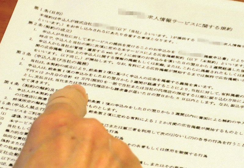 求人サイトの運営会社から送られてきた規約書を示す薬局の担当者。「自動で有料になるという説明は事前に一切なかった」と訴える=佐賀県で2019年6月8日、石井尚撮影(画像の一部を加工しています)