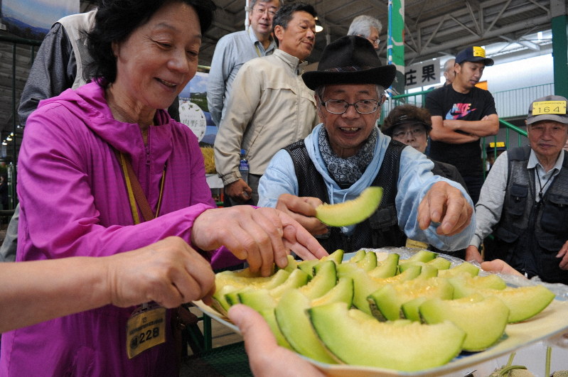 初競り前に振る舞われたメロンに手を伸ばす青果店主ら=山形県三川町で2019年6月13日、長南里香撮影