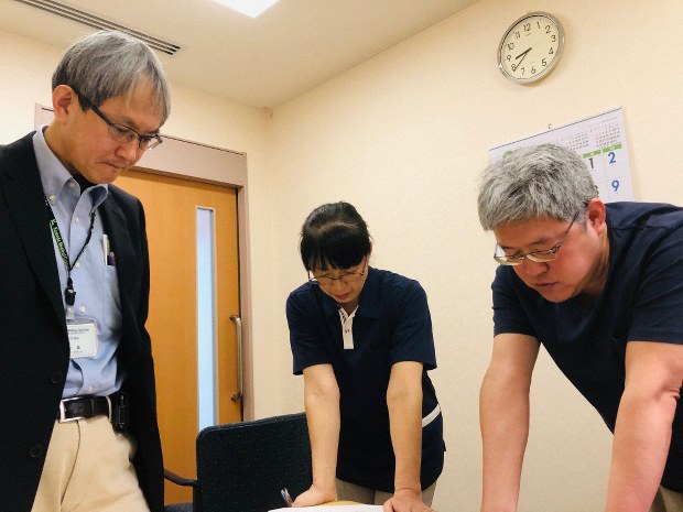 医師と看護師でその日の診療先と時間を打ち合わせる。左端が大川薫医師=千葉県鴨川市の亀田総合病院で