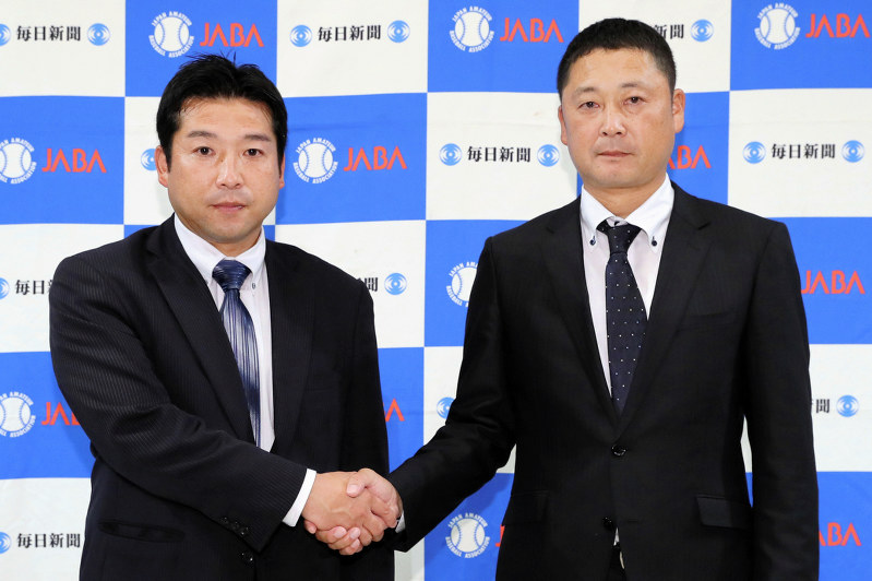 初戦での対戦が決まり、握手を交わす七十七銀行の小河義英監督(左)とヤマハの室田信正監督=東京都千代田区で吉田航太撮影